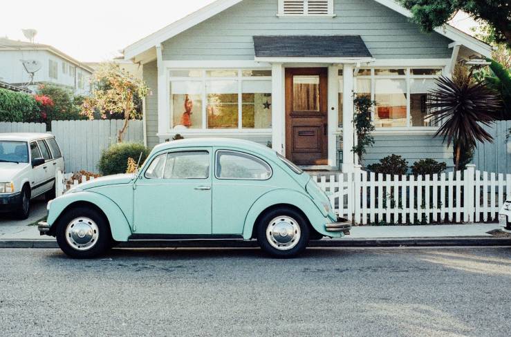 A light blue car parked in front of a house.